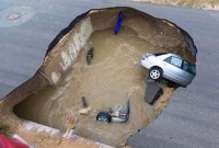 রাস্তার মধ্যে বিশাল গর্ত, তলিয়ে গেল দুটি গাড়ি!