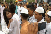 ঈদে লাইন ধরে দাঁড়িয়ে থাকা যুবকদের সঙ্গে কোলাকুলি করছেন তরুণী