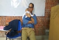 সন্তানকে শিক্ষকের কোলে রেখে পরীক্ষা দিচ্ছেন ছাত্রী