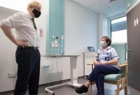 চেয়ারে বসে কথা বলছেন নার্স, দাঁড়িয়ে থেকে শুনছেন ব্রিটিশ প্রধানমন্ত্রী